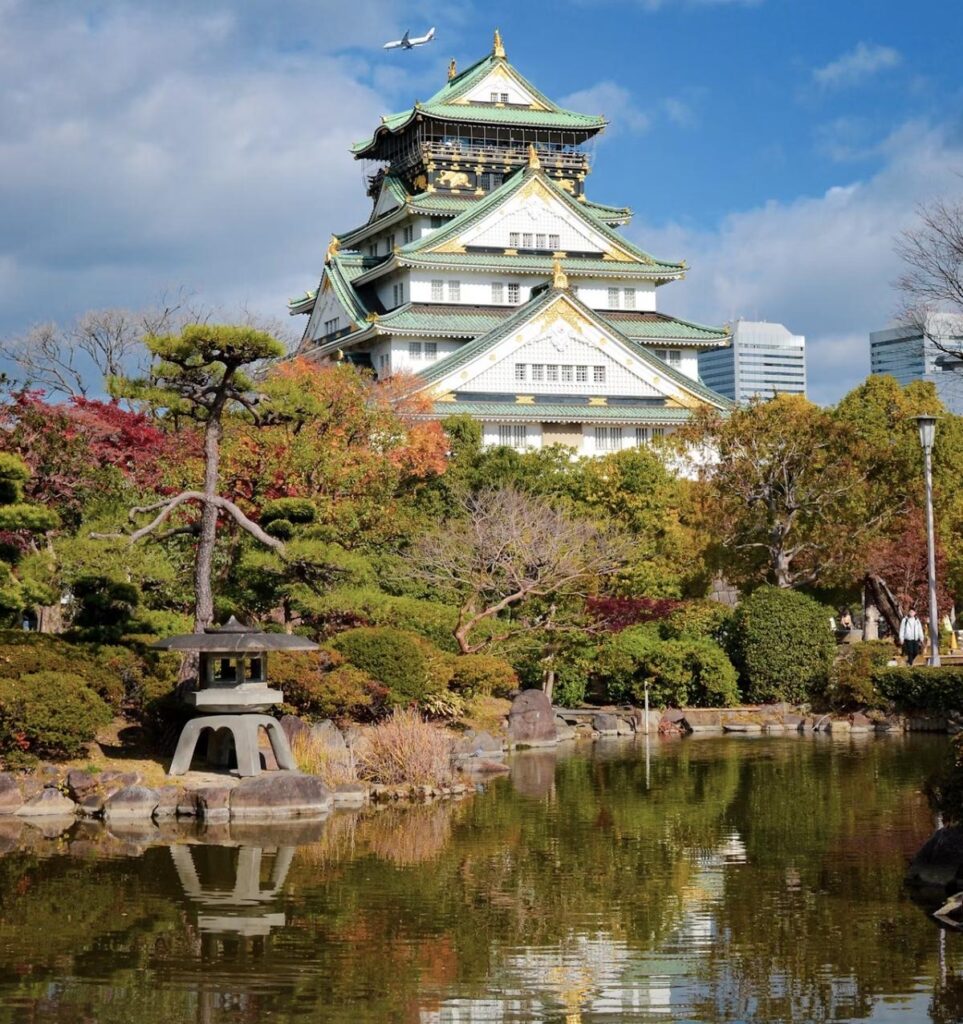 Osaka Castle framed by autumn foliage, reflected in the moat